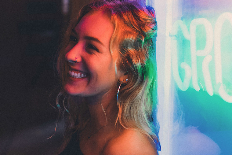 Lächelnde Frau mit Neon-Schriftzug 